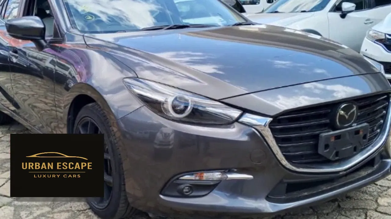 Mazda Axela in grey, front three-quarter close-up showing the headlight and grille
