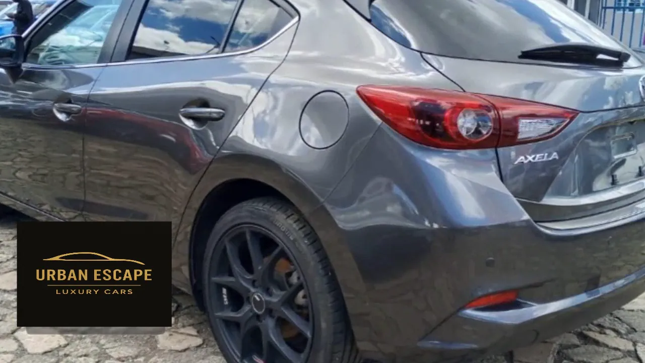 Mazda Axela hatchback in grey, rear three-quarter close-up with tail light, Axela badge and black alloy wheel
