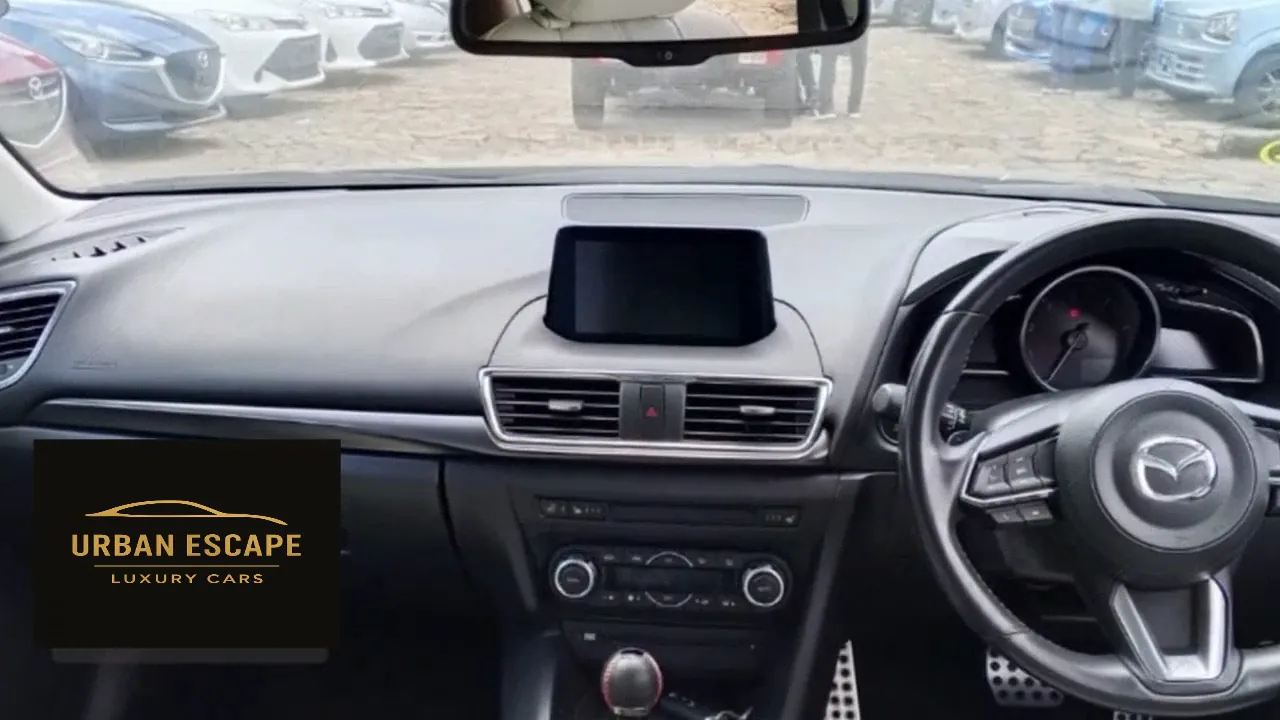 Mazda Axela dashboard in black with centre screen, right-hand drive steering wheel and drilled pedals