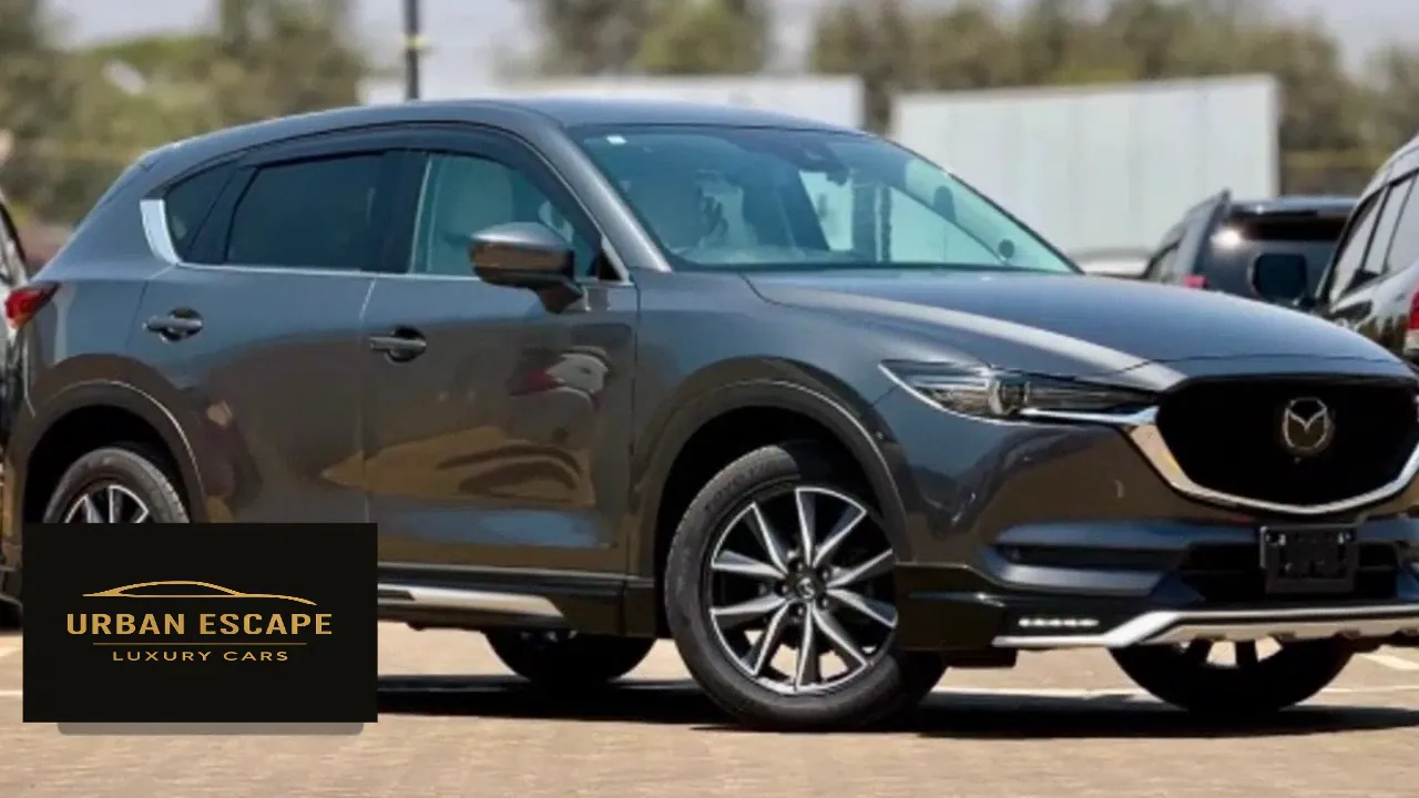 Mazda CX-5 in dark grey, front three-quarter view with alloy wheels, chrome grille surround and headlights