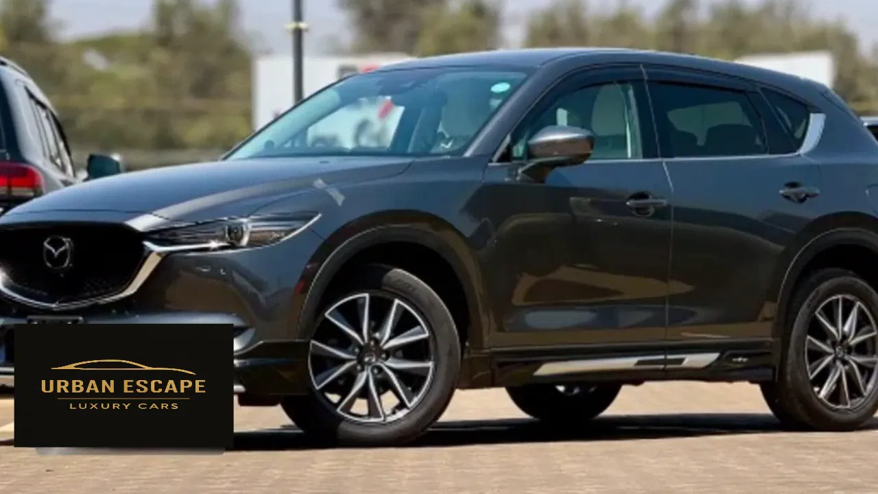 Mazda CX-5 in dark grey, side view from the front left with alloy wheels and silver lower door trim