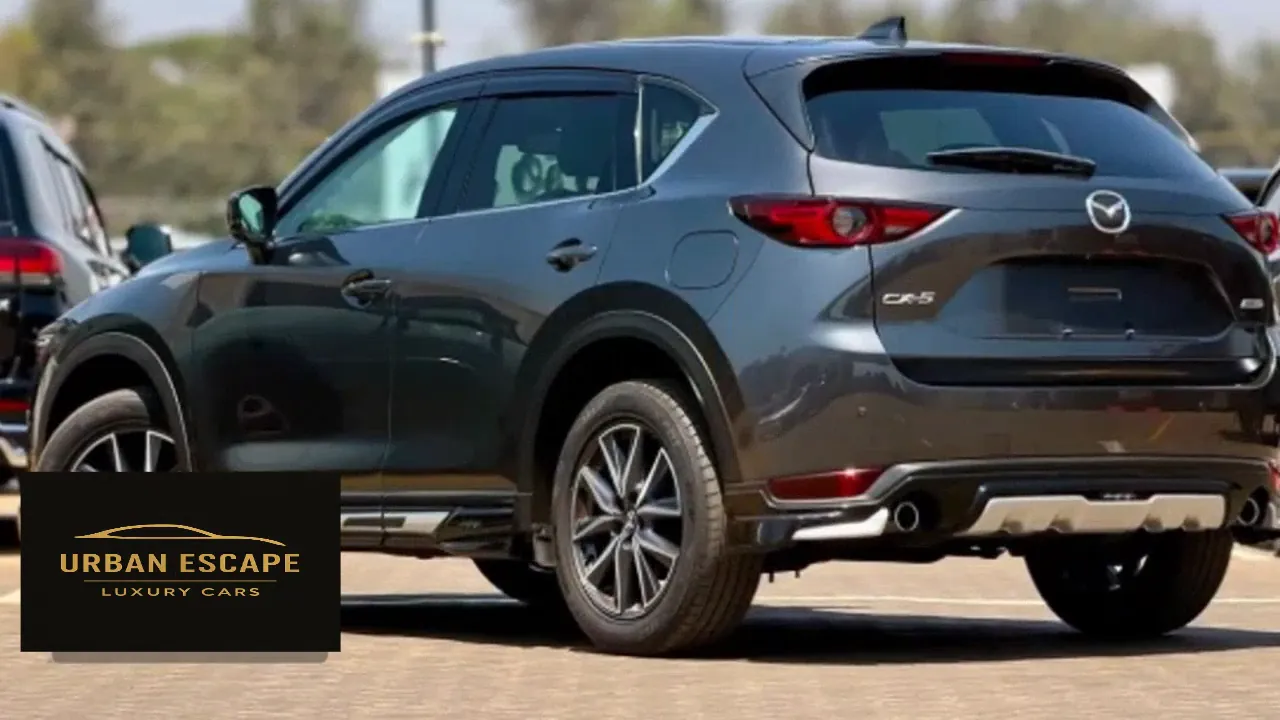 Mazda CX-5 in dark grey, rear three-quarter view with roof spoiler and twin exhaust tips