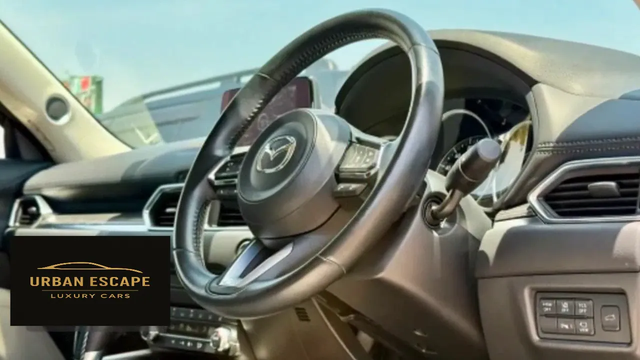 Mazda CX-5 stitched leather steering wheel with control buttons, seen from the driver's door