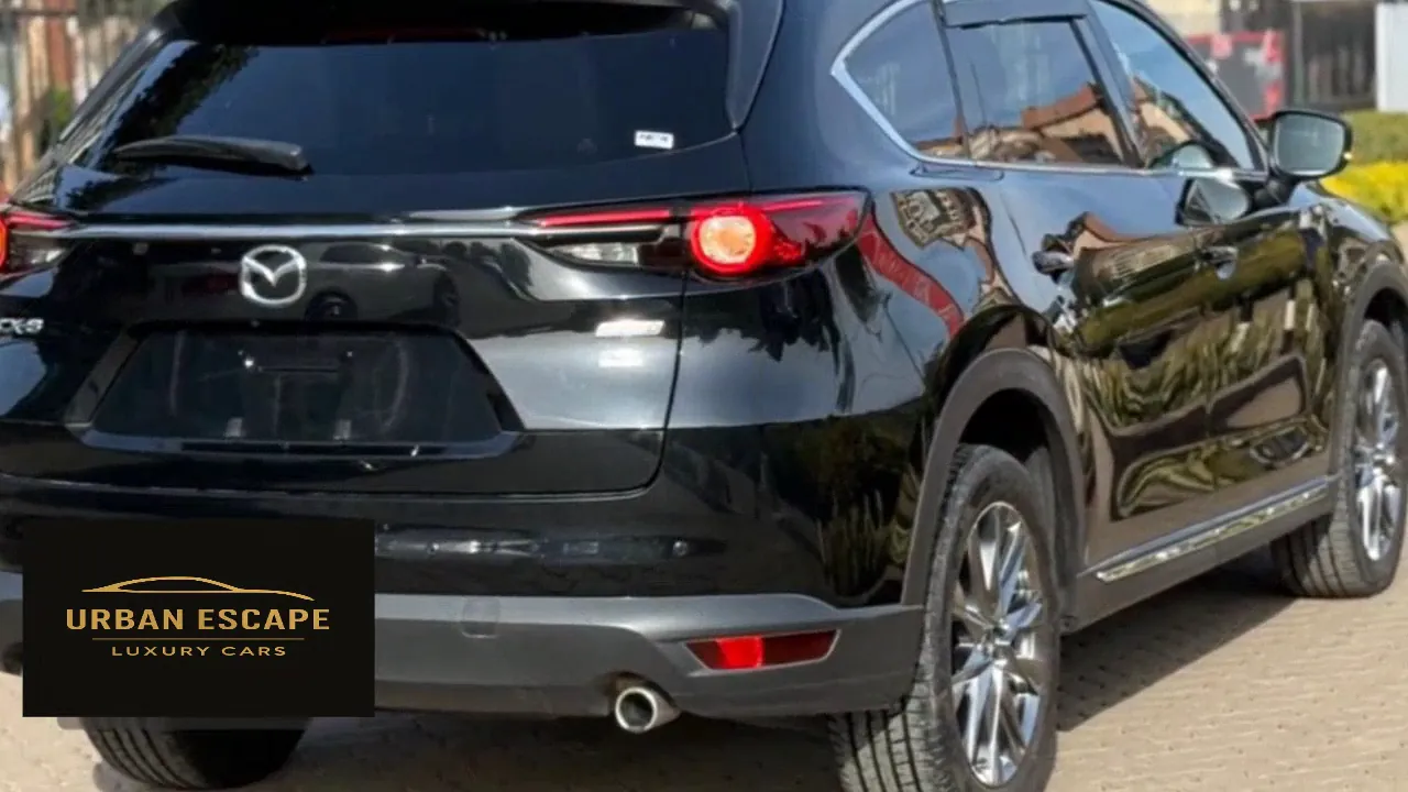 Mazda CX-8 in black, rear three-quarter view with tail lights on, CX-8 badge and alloy wheels