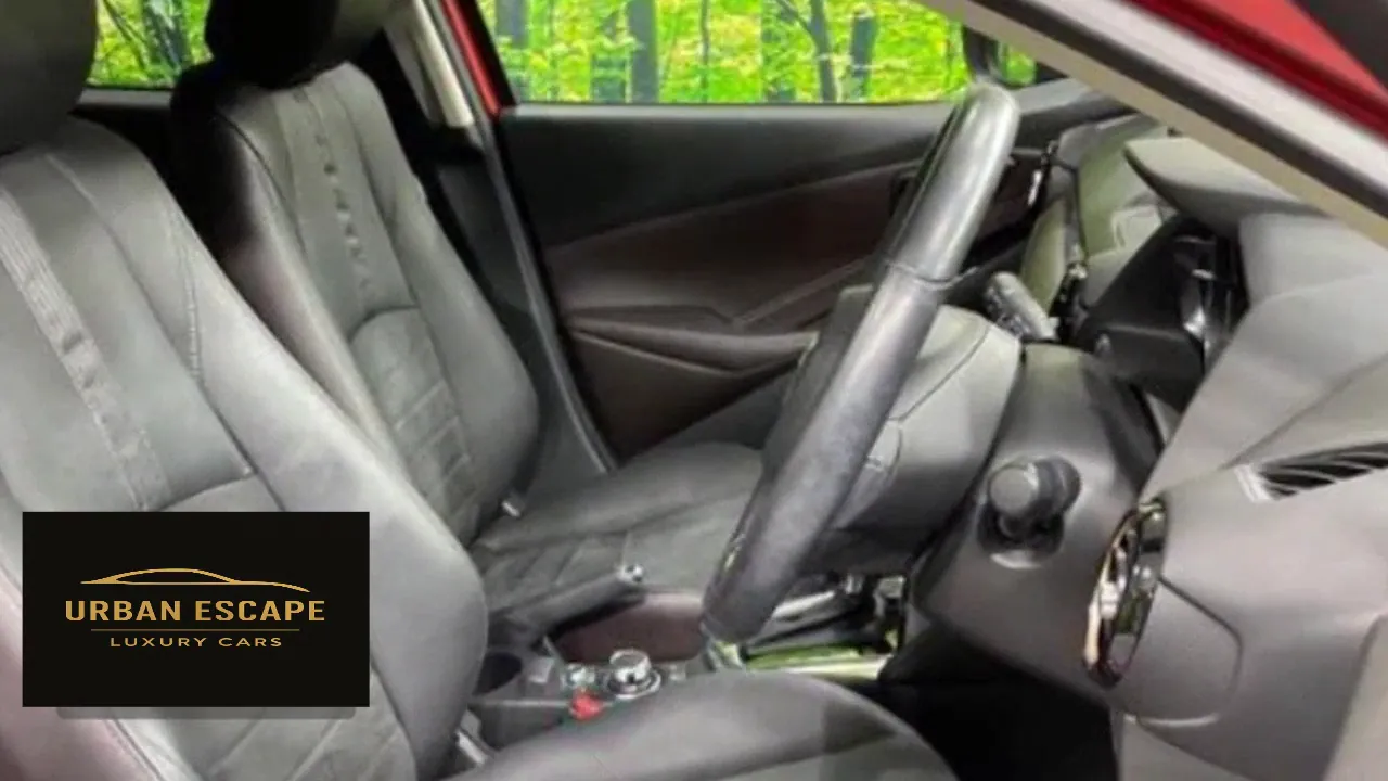 Mazda Demio in red, dark grey front seats and steering wheel seen through the open door