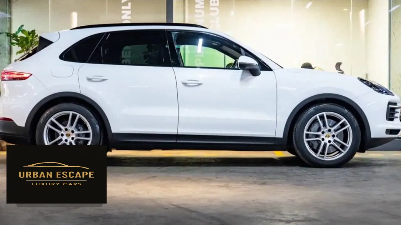 Porsche Cayenne in white, side profile in a showroom with silver alloy wheels and dark tinted rear windows