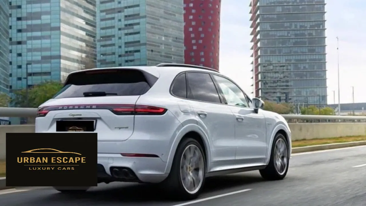 Porsche Cayenne in white on a city road, rear three-quarter view with full-width rear light strip