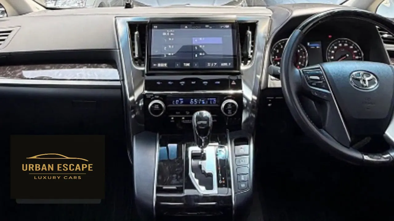 Toyota Alphard dashboard in black with centre screen, wood-effect trim and right-hand-drive steering wheel