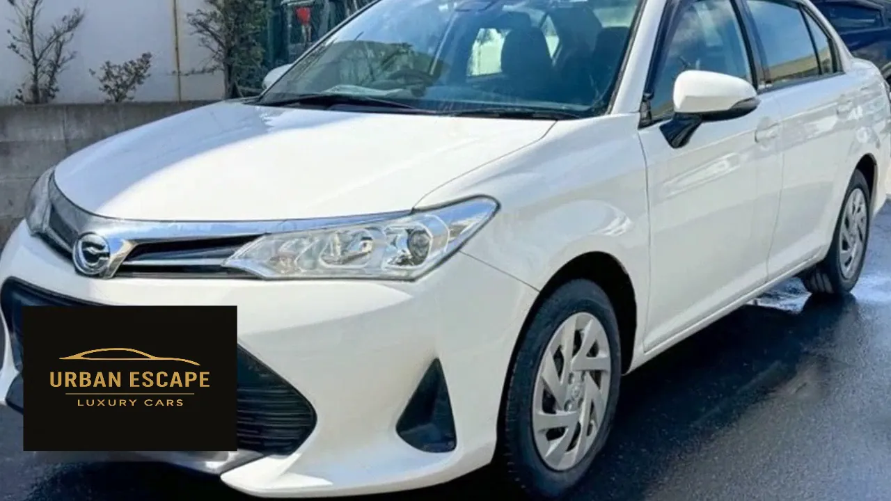 Toyota Axio in white, front three-quarter view of the left side with chrome grille and silver wheel covers