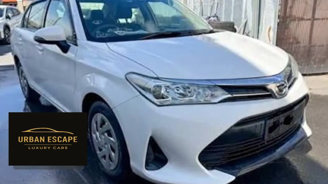 Toyota Axio in white, front three-quarter view of the right side showing the headlight and chrome grille