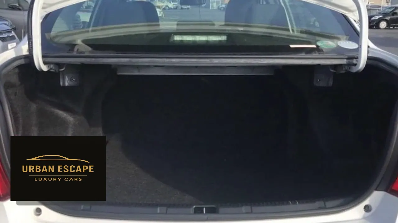 Toyota Axio in white from behind with the boot lid open, showing the carpeted boot space