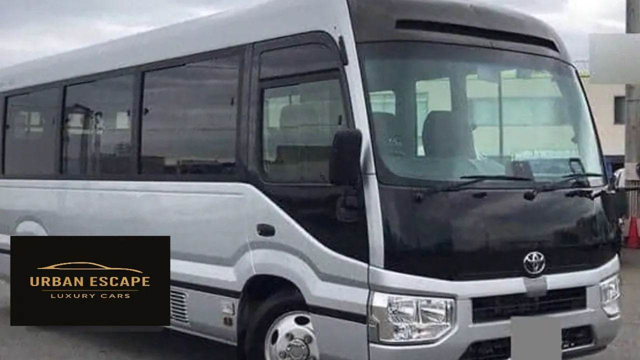 Toyota Coaster in silver with a black front panel, front three-quarter view