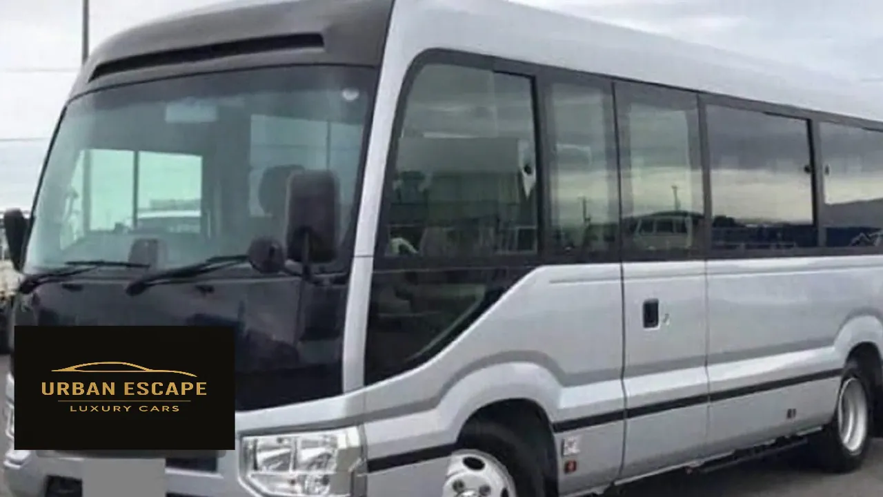 Toyota Coaster in silver, front three-quarter view from the left showing the side door