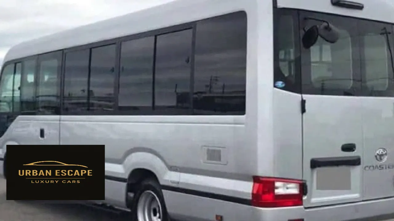 Toyota Coaster in silver, rear three-quarter view showing the rear door, tail light and Coaster badge