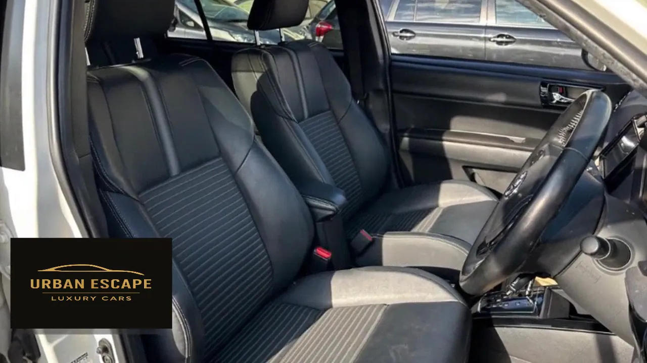 Toyota Corolla Fielder dark front seats with striped centre panels, seen through the open front door