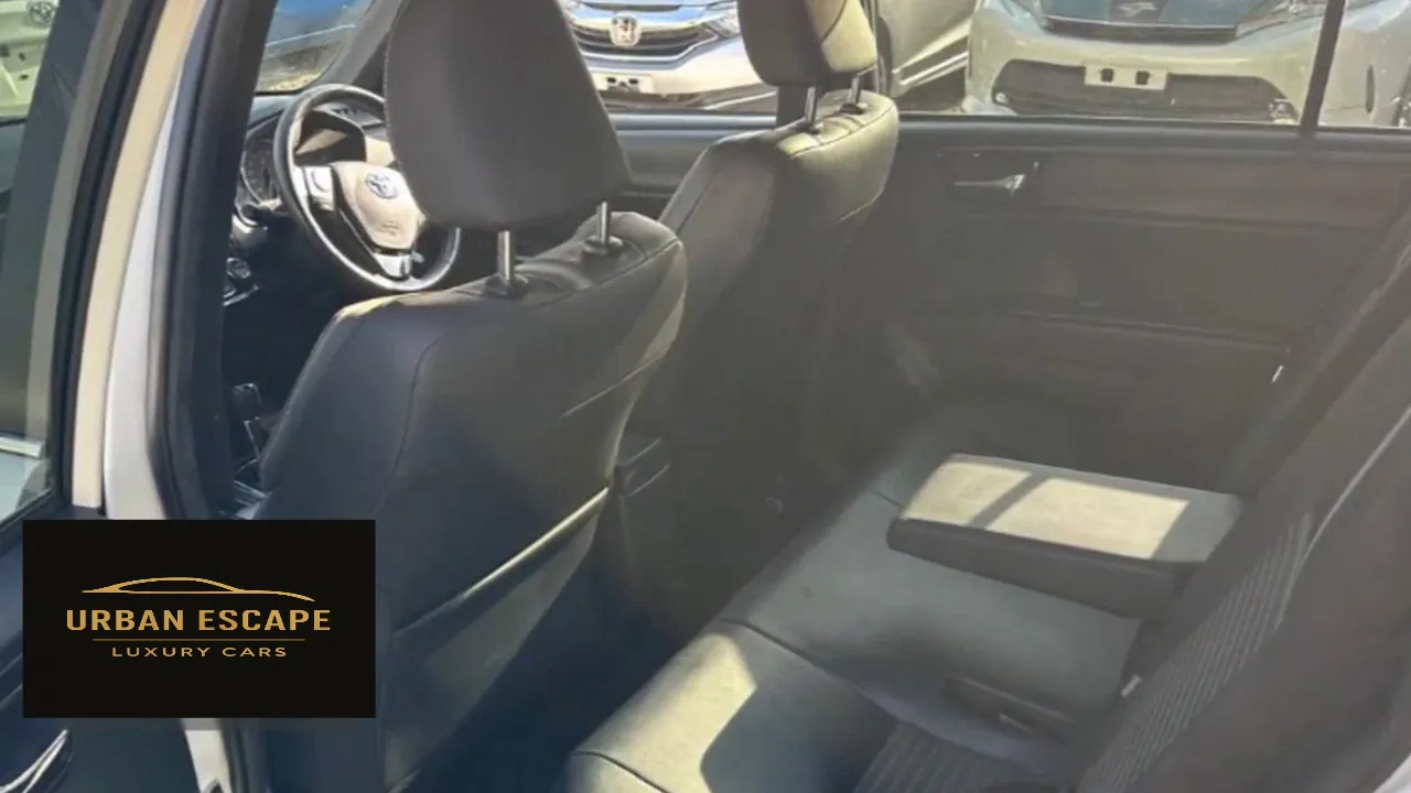 Toyota Corolla Fielder dark back seats with the centre armrest folded down, seen through the open rear door