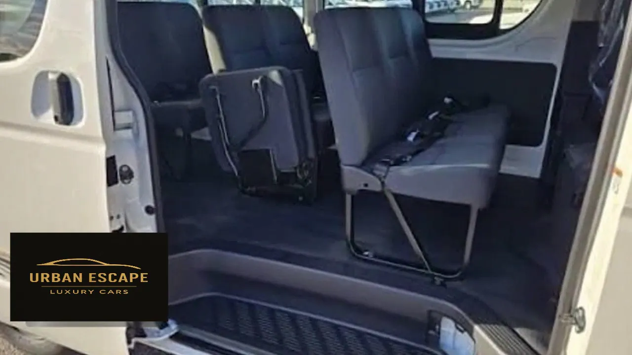 Toyota Hiace Safari Van in white, sliding door open showing grey bench seats and a folded jump seat