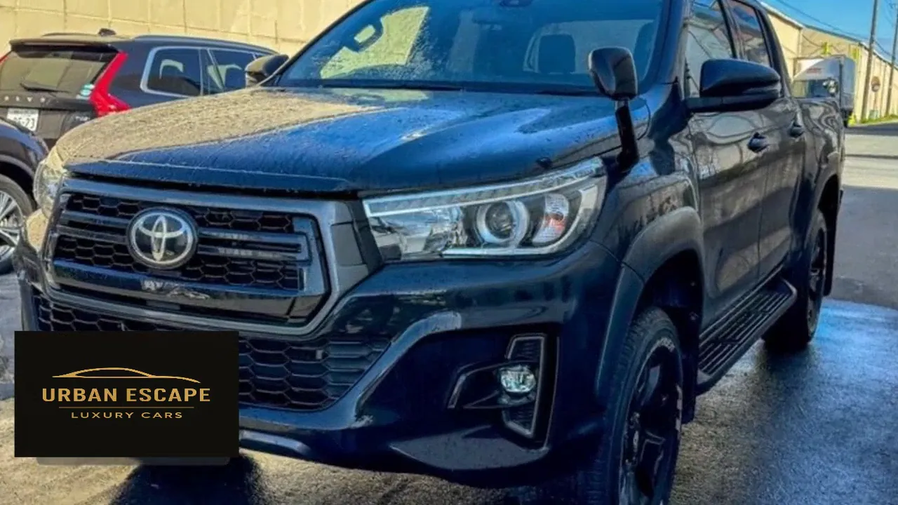 Toyota Hilux Double Cab in black, front three-quarter view with chrome-trimmed grille and black alloy wheels