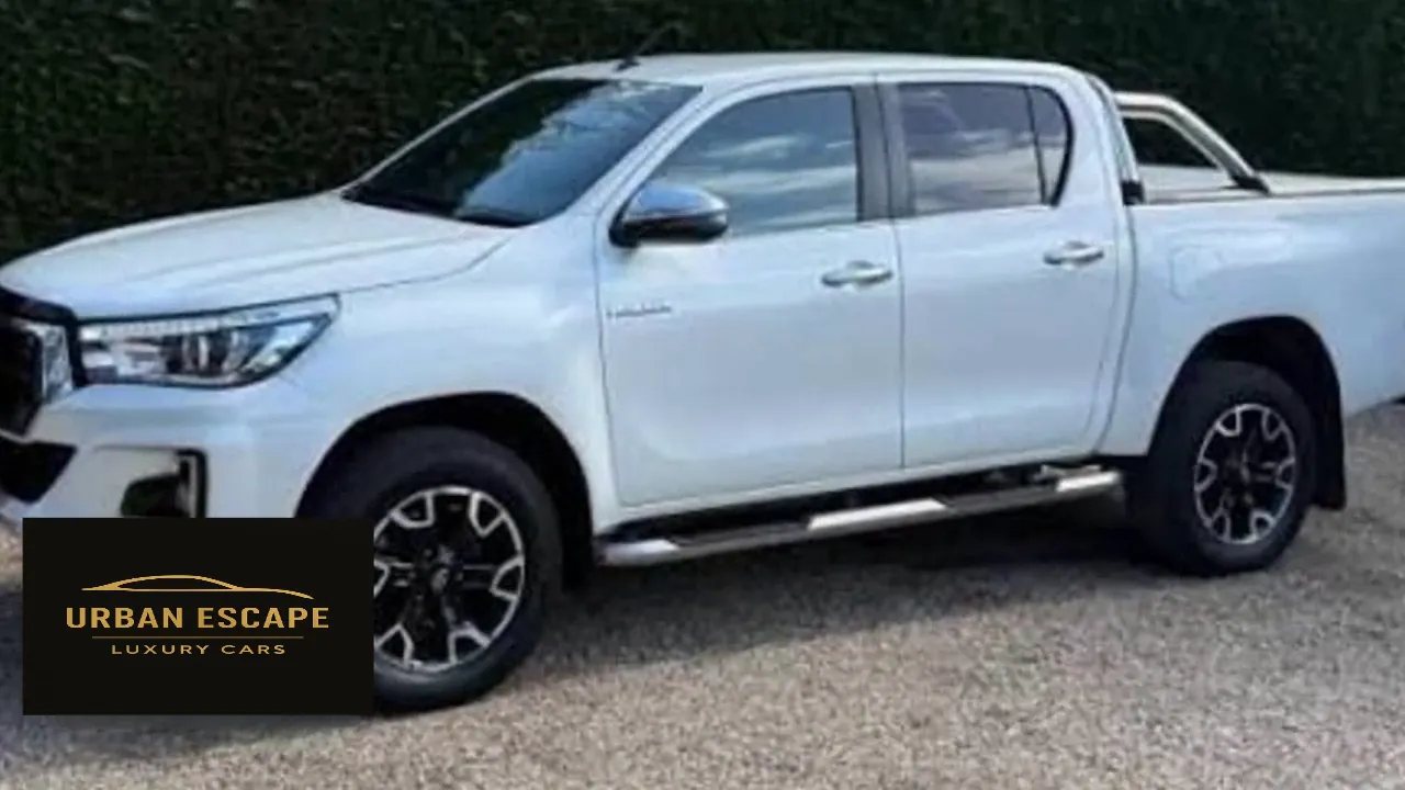 Toyota Hilux Double Cab in white, side view with side steps, alloy wheels and sports bar