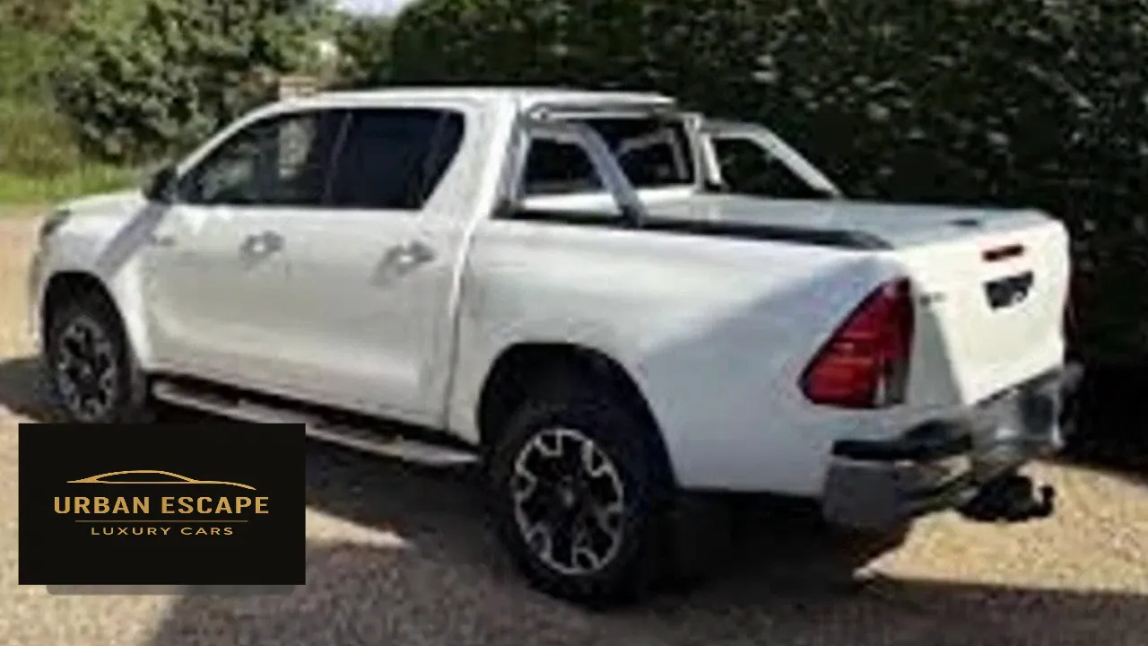 Toyota Hilux Double Cab in white, rear three-quarter view with sports bar and tow bar