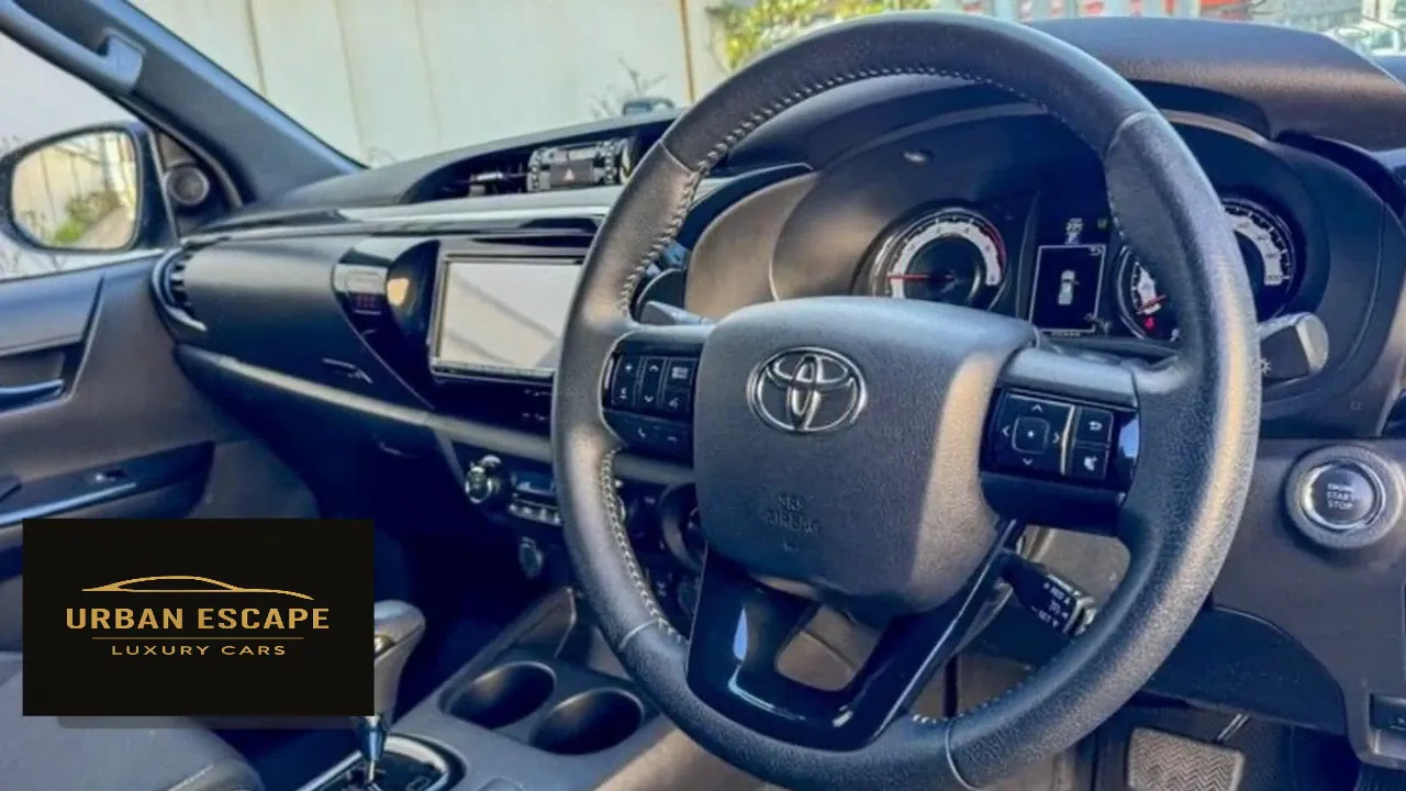 Toyota Hilux Double Cab dashboard with stitched steering wheel, centre screen and start button, right-hand drive