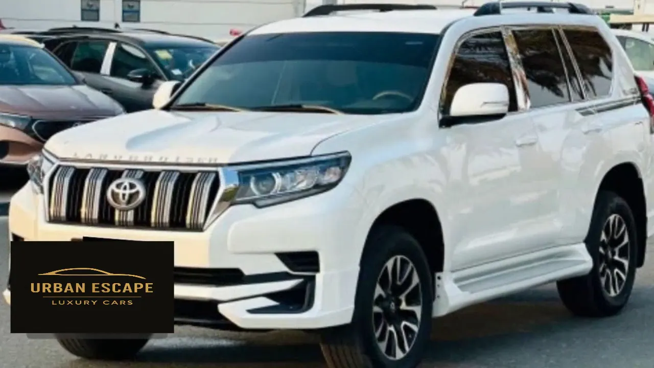 Toyota Land Cruiser Prado in white, close front view showing chrome grille, headlamps and side steps