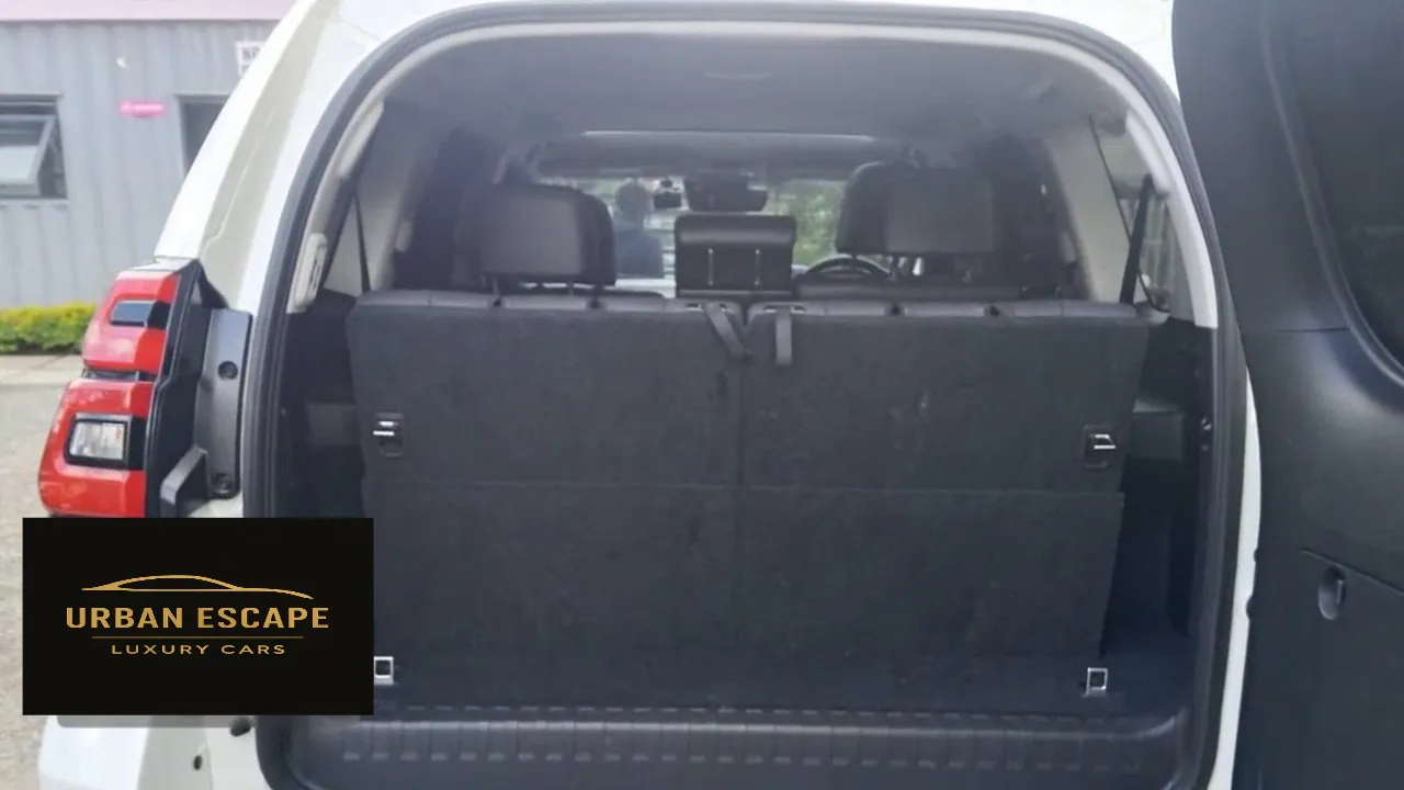 Toyota Land Cruiser Prado in white with side-hinged rear door open, showing the carpeted boot space